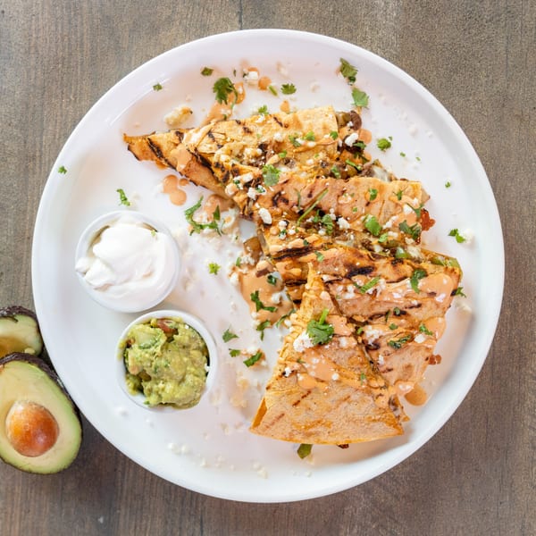 Dahlia's quesadilla with chipotle sauce, cotija cheese, cilantro, guacamole, and sour cream.