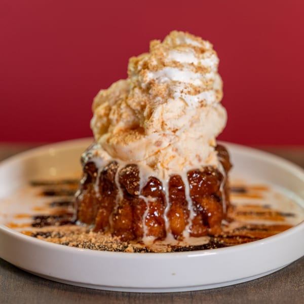 Dahlia's Mexican dessert, a golden-brown cake topped with vanilla ice cream, whipped cream, and drizzles.