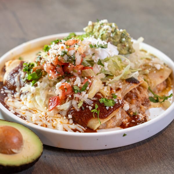 Dahlia's enchiladas topped with red sauce, lettuce, pico de gallo, cheese, guacamole, and sour cream.