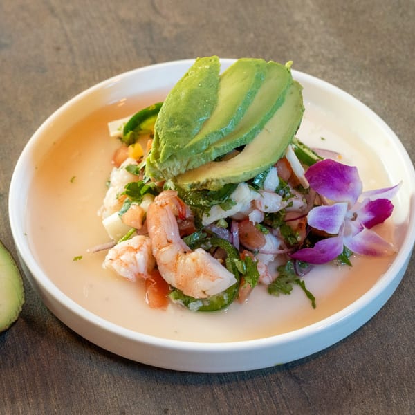 Dahlia's Mexican ceviche with shrimp, avocado, and a purple orchid garnish in a white bowl.